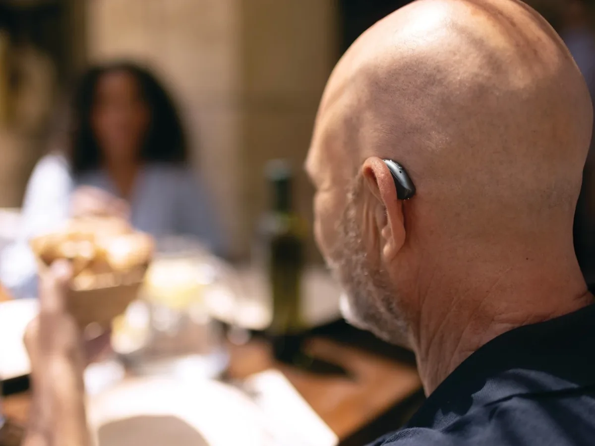 Man wearing a Phonak hearing aid on a restaurant terrace