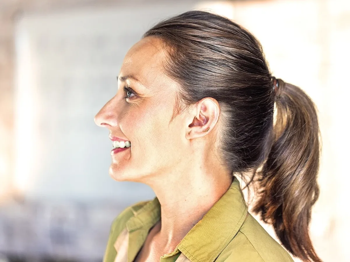 Profile of a woman wearing an invisible Phonak Lyric hearing aid, smiling outdoors